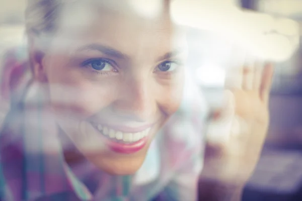 Gebückte hübsche Frau, die durch das Glas schaut — Stockfoto