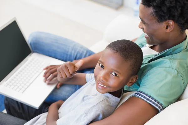 Pai e filho usando laptop no sofá — Fotografia de Stock