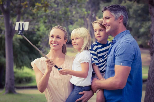 Família feliz usando um pau de selfie no parque — Fotografia de Stock