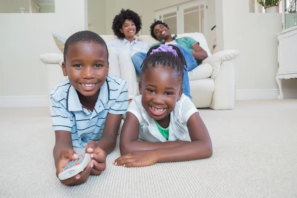 Happy sourozenci leží na podlaze, sledování televize — Stock fotografie