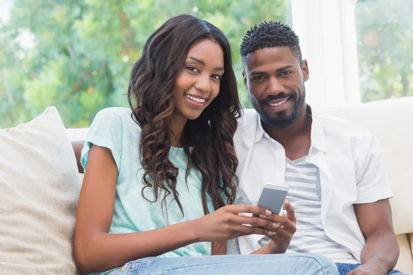 Casal feliz no sofá usando telefone — Fotografia de Stock