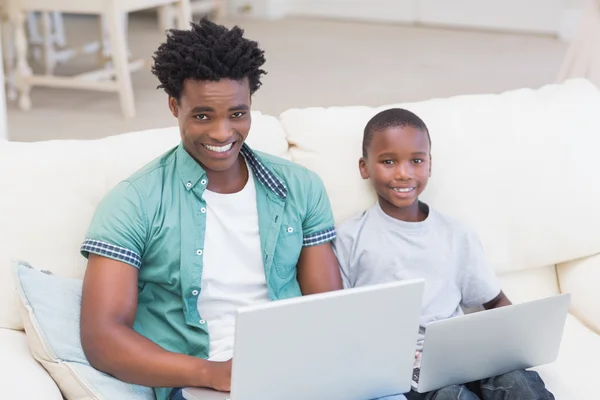 Father and son using laptops on the couch — Stock Photo, Image