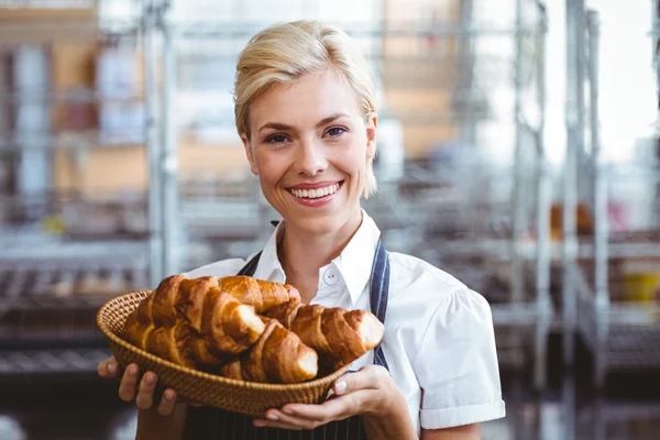 Garçonete lindo alegre segurando uma cesta com croissant — Fotografia de Stock