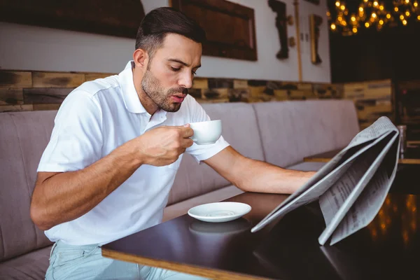 Joven bebiendo taza de café leyendo el periódico — Foto de Stock