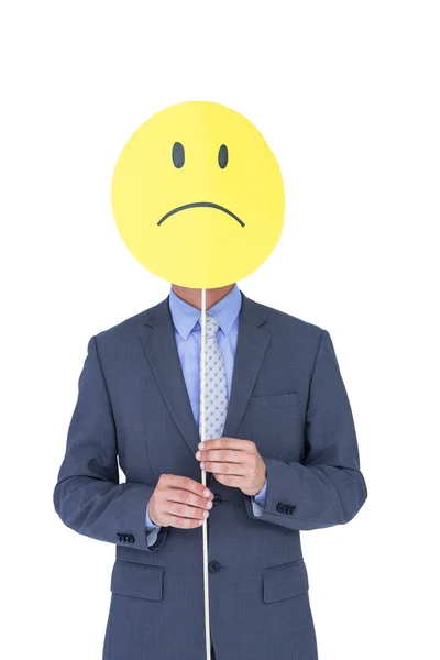 Affärsman med ledsen smiley inför ballong på skrivbord — Stockfoto
