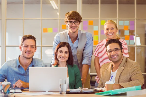 Счастливая творческая бизнес-команда, использующая ноутбук во время встречи — стоковое фото