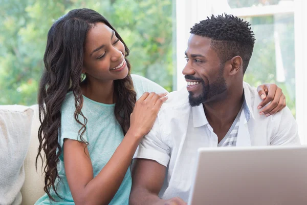 Casal feliz no sofá usando laptop — Fotografia de Stock