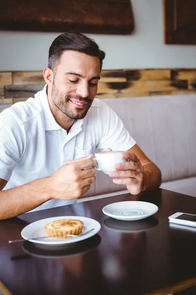 若い男が飲むコーヒーとペストリーの横にあります。 — ストック写真