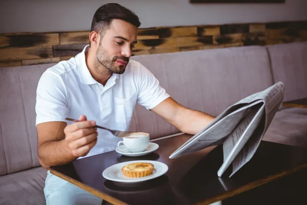 Young man having cup of coffee reading newspaper — Stock Photo, Image