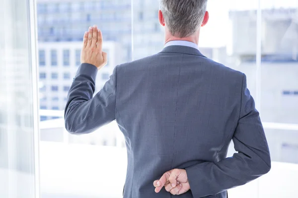 Businessman making a oath while crossing fingers — Stock Photo, Image