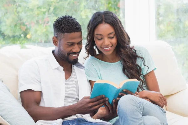 Pareja feliz leyendo en el sofá — Foto de Stock