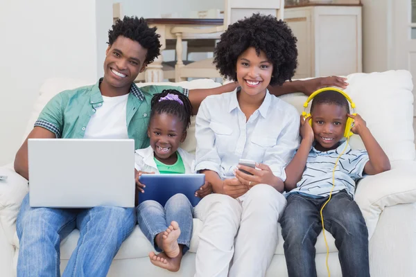 Familia feliz usando tecnologías en el sofá — Foto de Stock