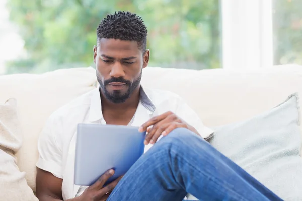 Man using his tablet on couch — Stock Photo, Image