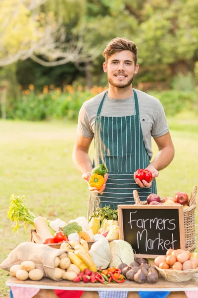 Pohledný farmář drží papriky — Stock fotografie