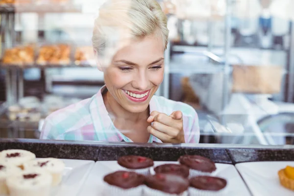 Pretty woman wijzend een cup-cake — Stockfoto