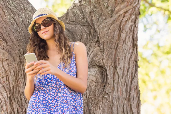 Pretty brunette texting in the park — Stock Photo, Image