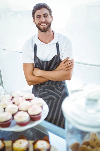 Smiling worker posing behind the counter arm crossed — Stock Photo, Image