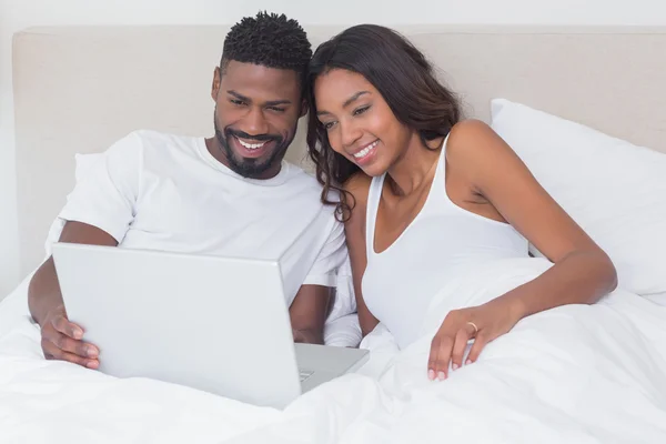 Casal relaxado usando laptop na cama juntos — Fotografia de Stock