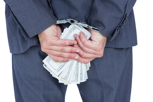 Businessman in handcuffs holding bribe — Stock Photo, Image