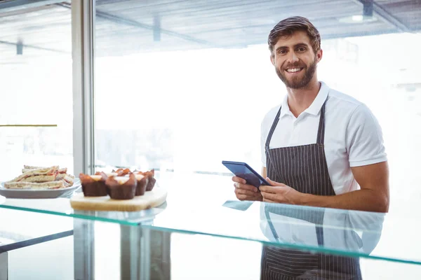 Handsome worker posing on the counter with a tablet — Stock Photo, Image