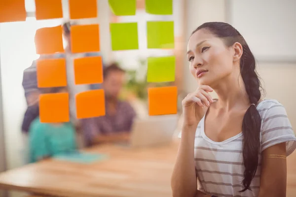 Businesswoman looking post its on the wall — Stock Photo, Image