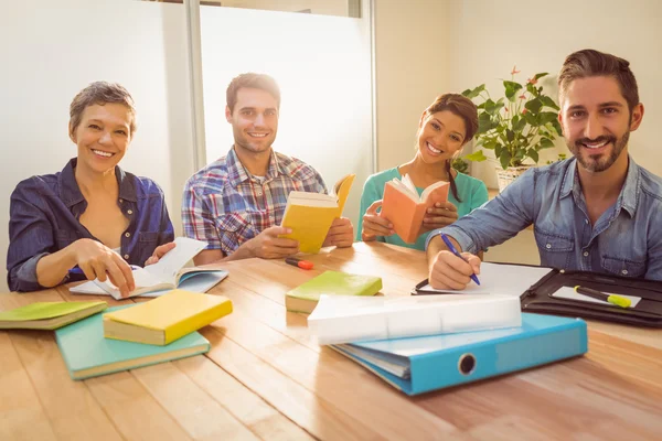 Group of colleagues reading books and smiling at camera — Stock Photo, Image
