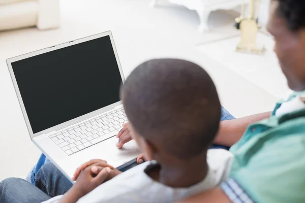 Pai e filho usando laptop no sofá — Fotografia de Stock