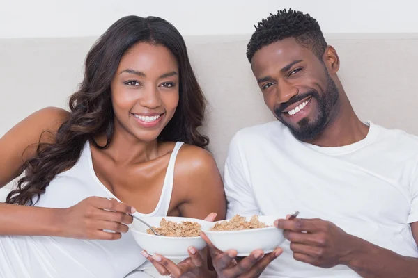 Casal relaxado na cama juntos comendo cereais — Fotografia de Stock