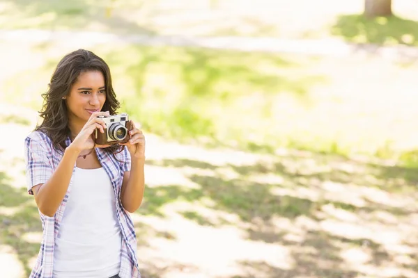 Ładna brunetka w parku przy użyciu kamery retro — Zdjęcie stockowe