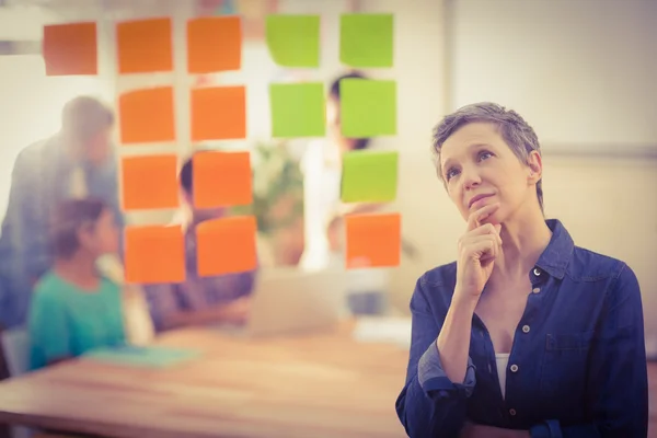 Businesswoman looking post its on the wall — Stock Photo, Image