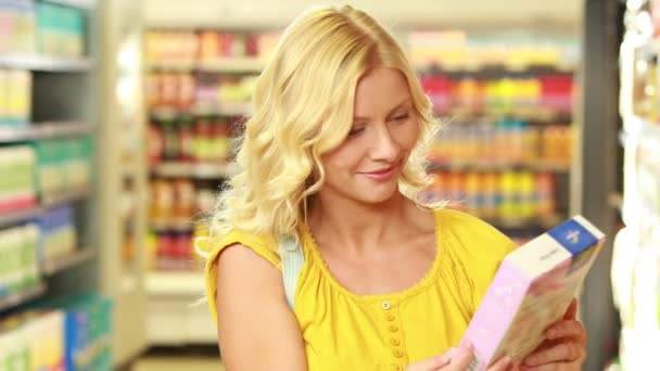 Pretty blonde putting product in trolley — Stock Video