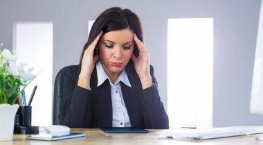 Stressed businesswoman working at desk clipart