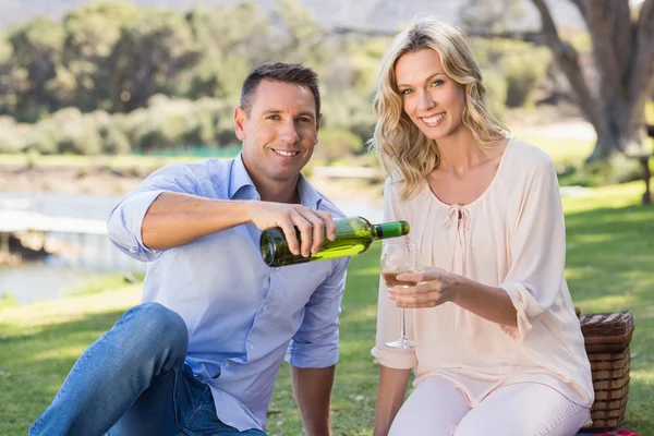 Paar sitzt und schenkt Wein in Glas ein — Stockfoto