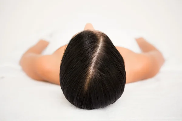 Morena deitado na mesa de massagem sorrindo — Fotografia de Stock