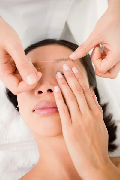 Hands threading beautiful woman's eyebrow — Stock Photo, Image