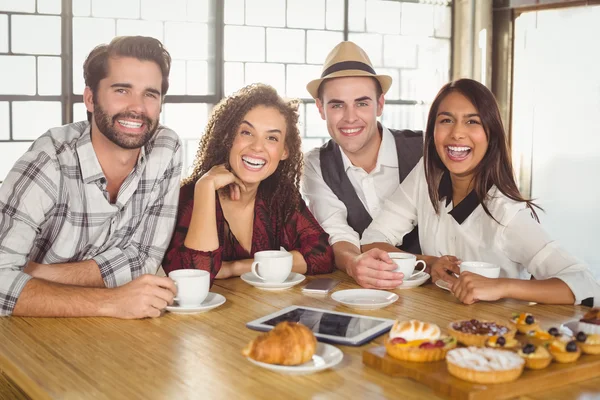 Amici che ridono gustando caffè e dolcetti — Foto Stock