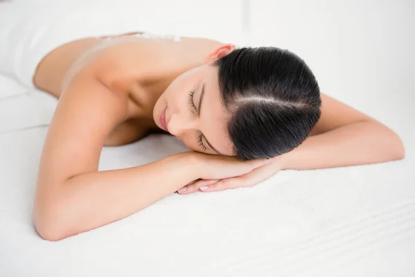 Morena deitado na mesa de massagem sorrindo — Fotografia de Stock