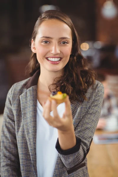 Usměvavá mladá žena ukazující muffin — Stock fotografie