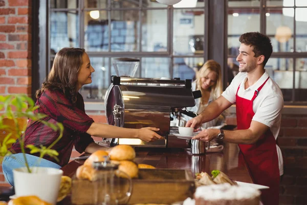 En leende barista serverar en klient — Stockfoto