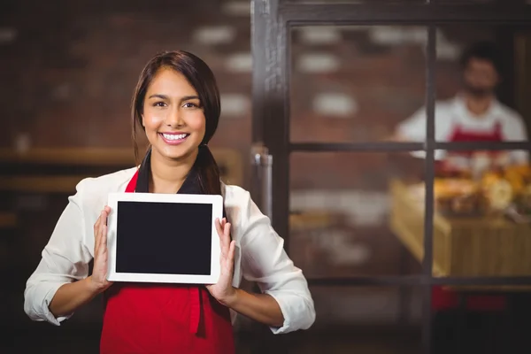 Leende servitris visar en digital tablet — Stockfoto