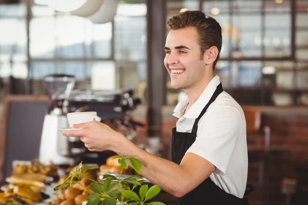 Usměvavý barista nabízí šálek kávy — Stock fotografie