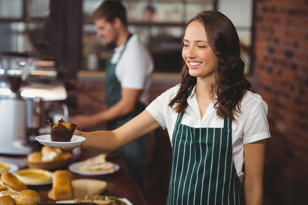 Lachende serveerster serveren een muffin — Stockfoto