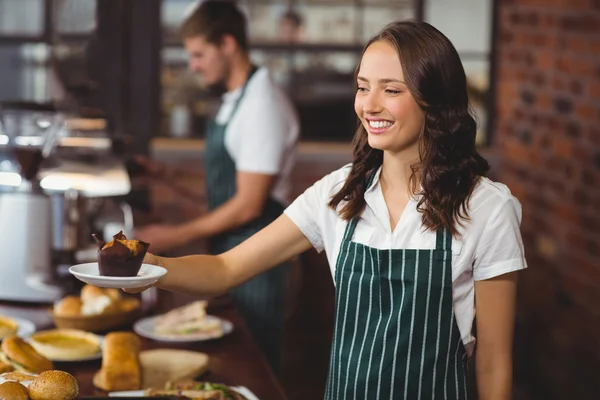 Smiling waitress serving a muffin — Stock Photo, Image