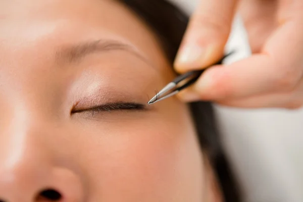 Woman placing fake eyelash on patient — Stock Photo, Image