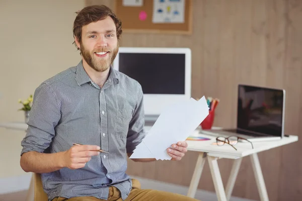 Hipster barbudo sonriendo a la cámara sosteniendo notas — Foto de Stock