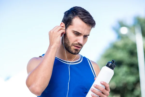 Een knappe atleet houdt een fles — Stockfoto