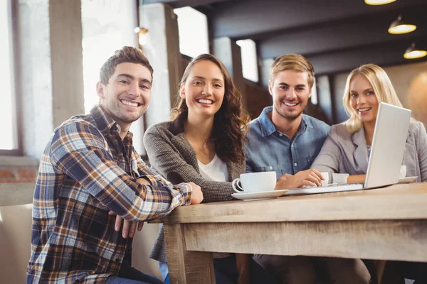 Amigos sonrientes tomando café y usando laptop — Foto de Stock