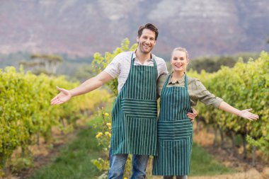 Two young happy vintners showing their fields clipart