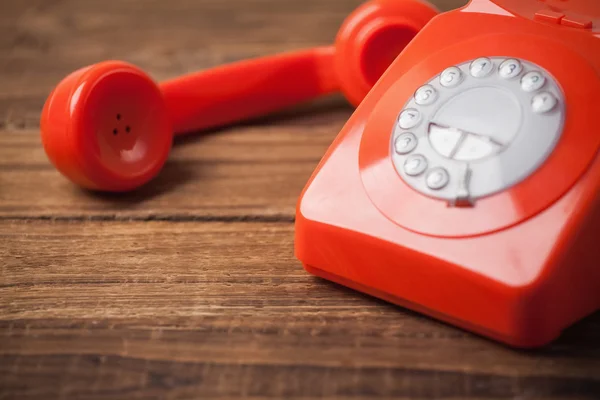 Červený telefon na dřevěný stůl — Stock fotografie