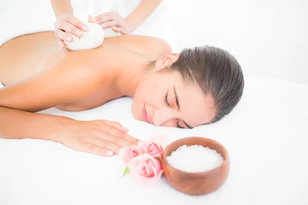 Brunette genieten van kruiden comprimeren massage — Stockfoto
